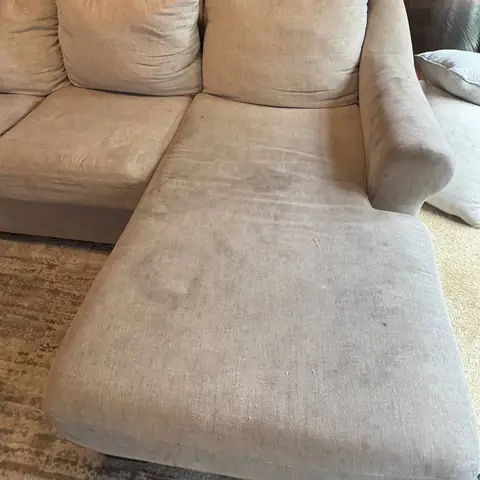 Beige sofa with chaise showing dark body-oil marks before cleaning